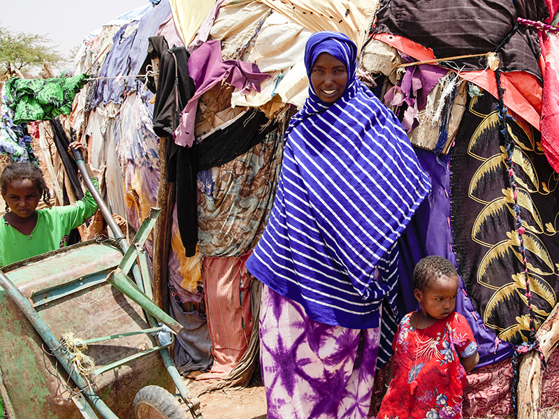 Mother and children in front of improvised shelters made with colorful textiles.