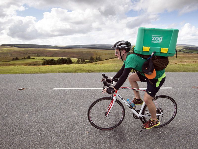 Man riding bicycle with a Shelter Box on his back