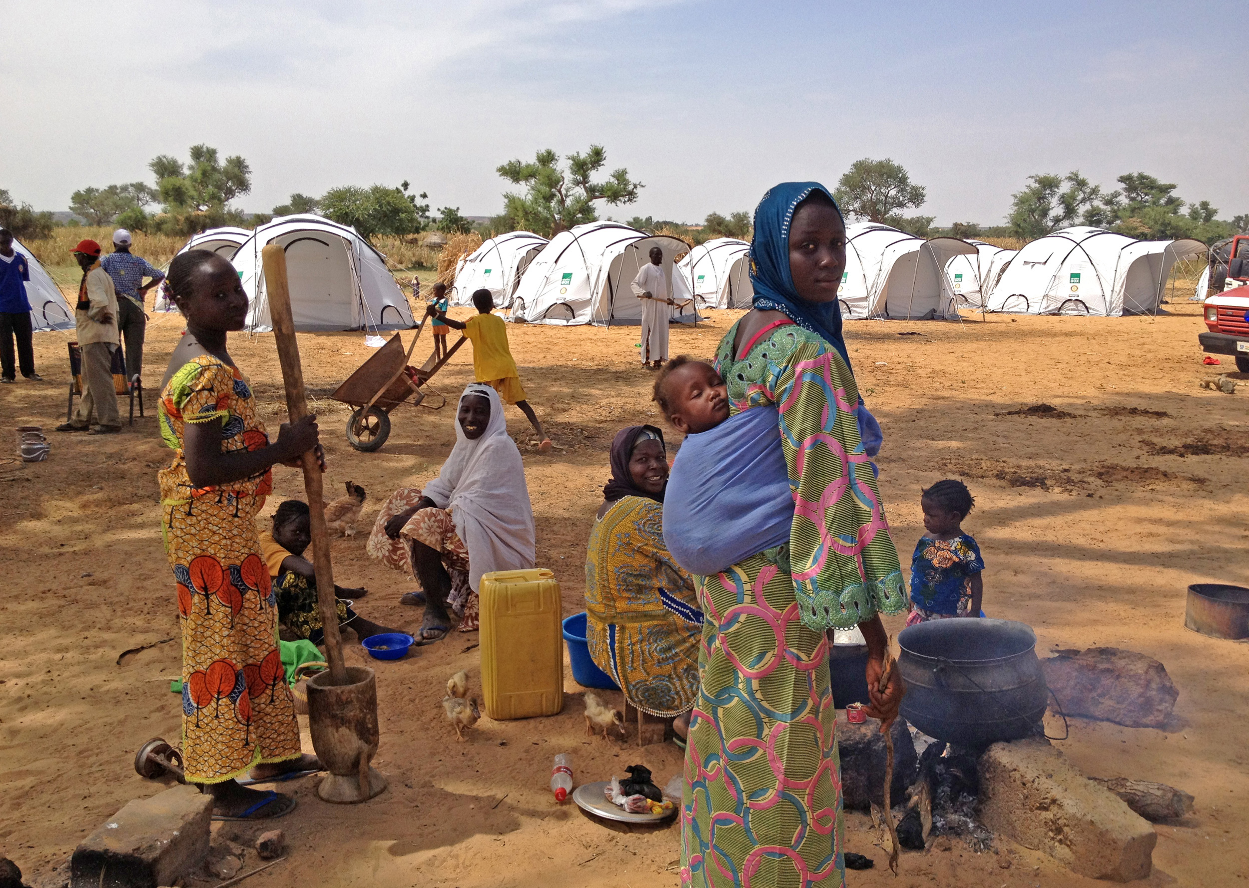 Woman carries child on back in camp with ShelterBox tents, Niger