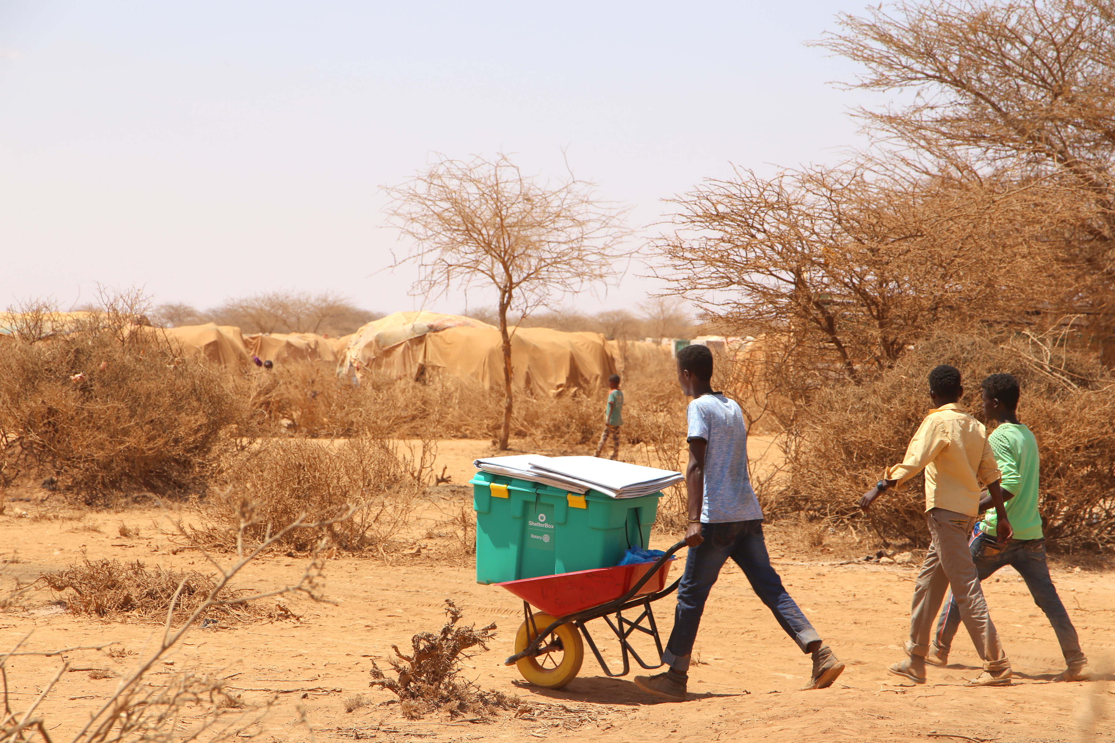 Family moves their ShelterBox across the arid landscape via wheelbarrow