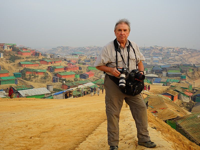 Tom with his camera on a hill overlooking neighborhood.