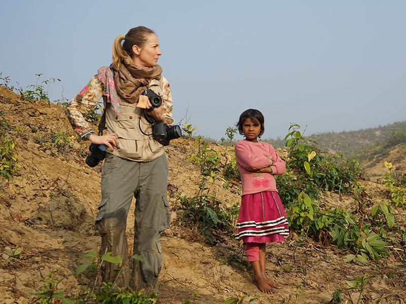 Veronique De Viguerie with camera on a hill next to child.