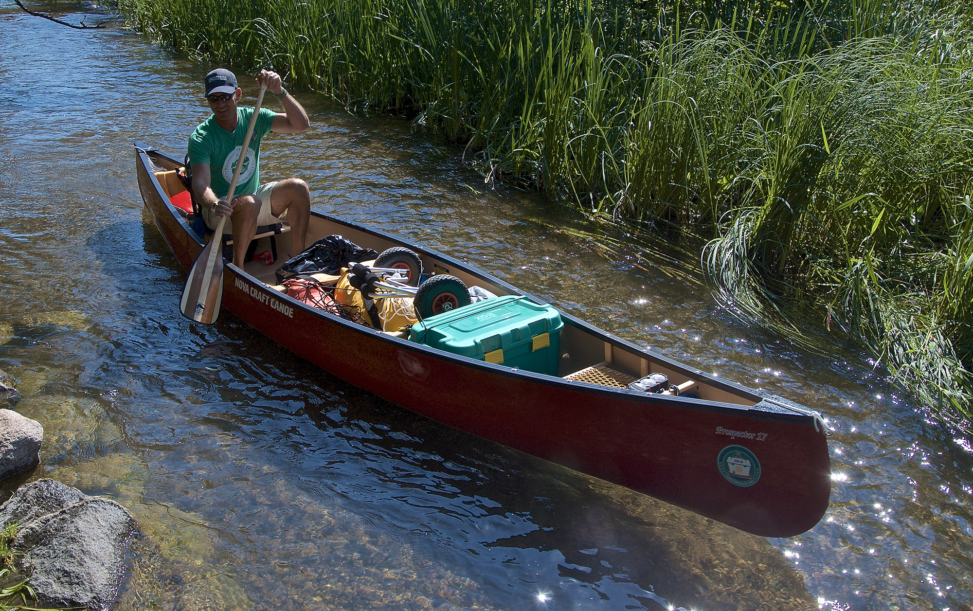 Erik and his canoe with sun shining on stream