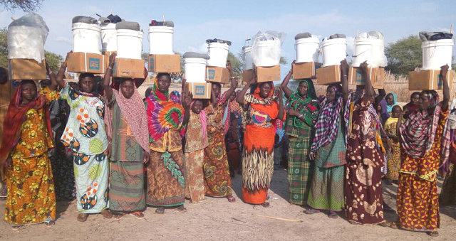 Chadian women holding ShelterBox aid items above their heads