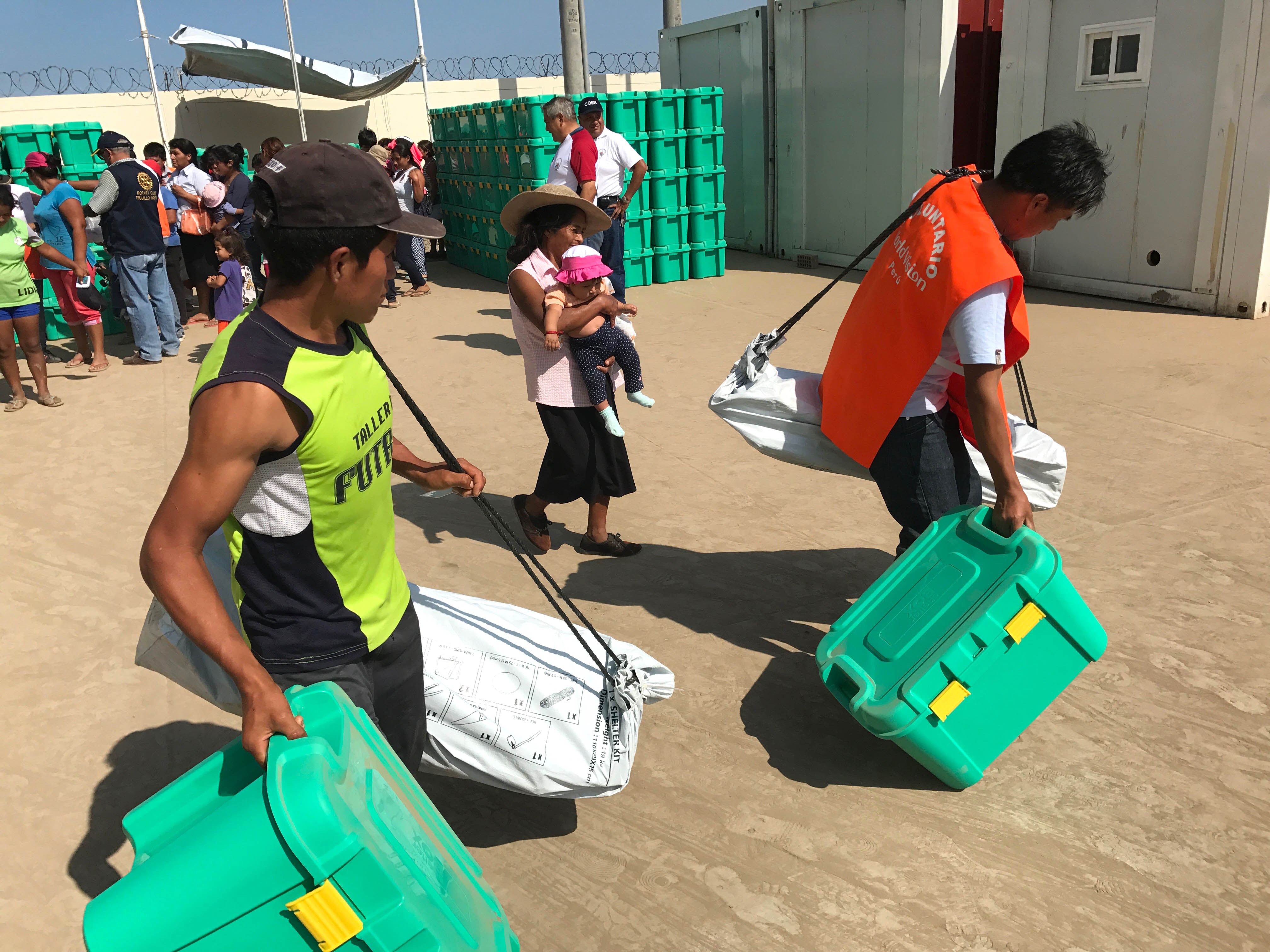 Young men carrying a full ShelterBox and ShelterKit each