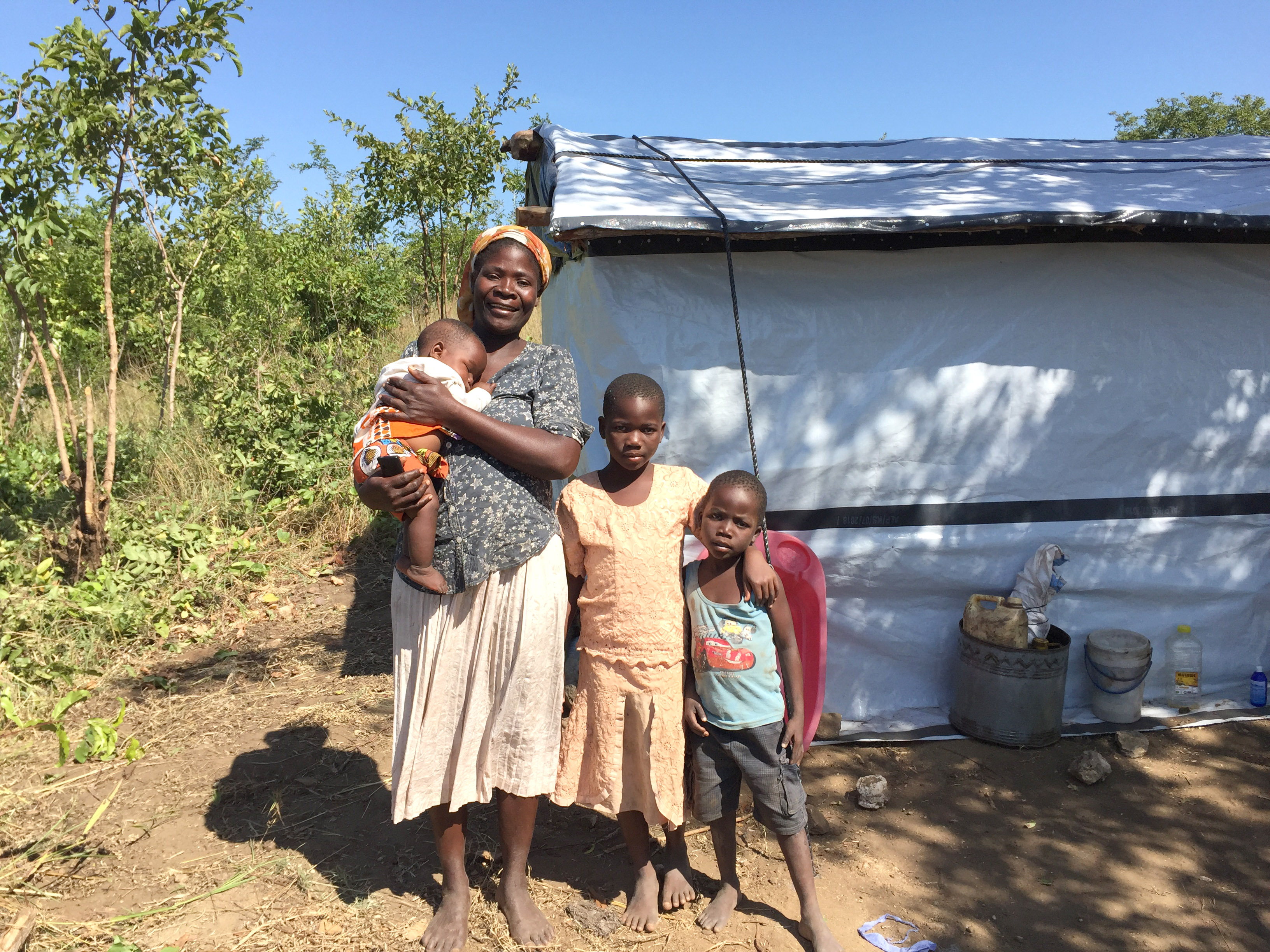 Family standing outside their home, repaired with ShelterKit