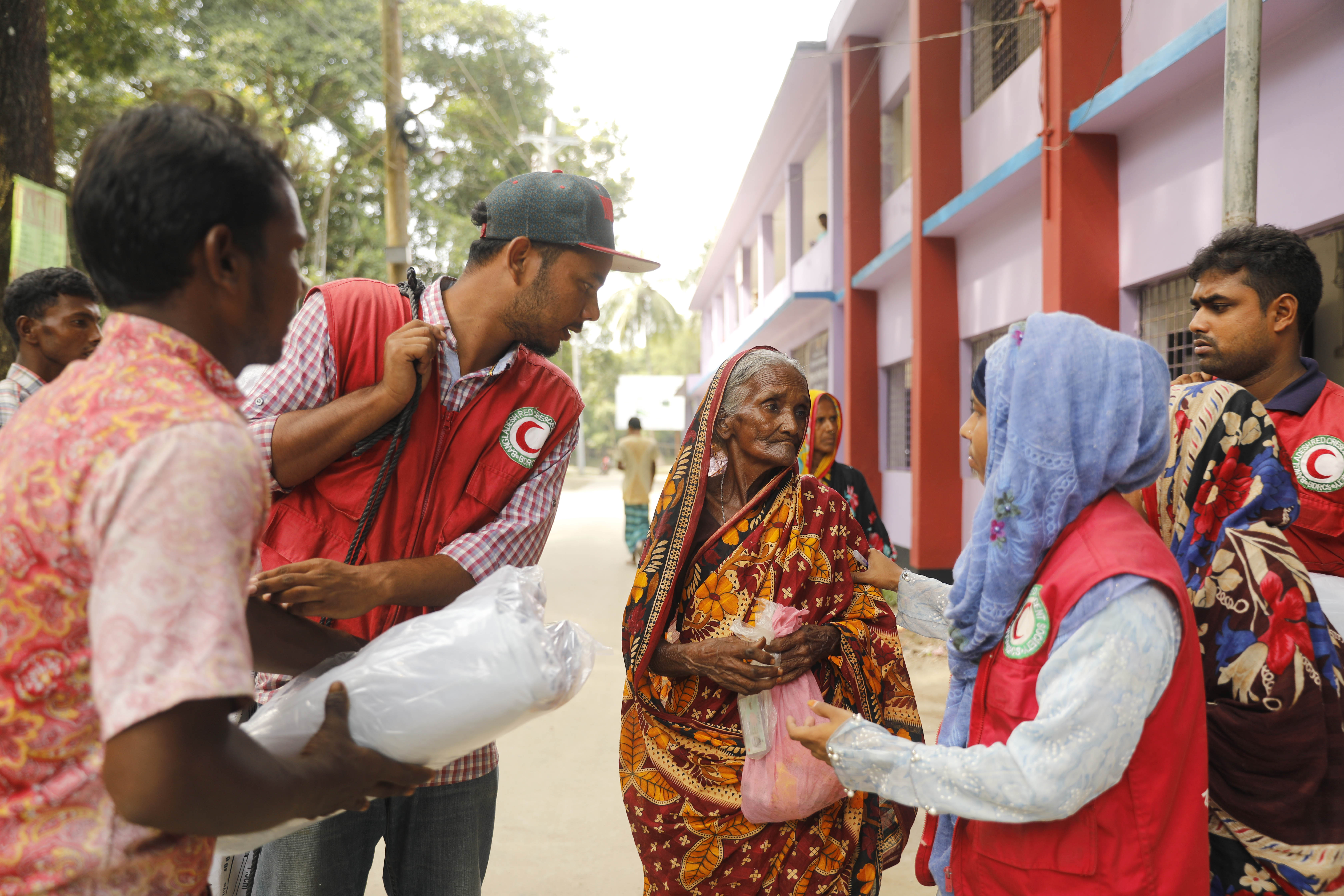 Members of the Bangladesh Red Crescent society help an elderly woman