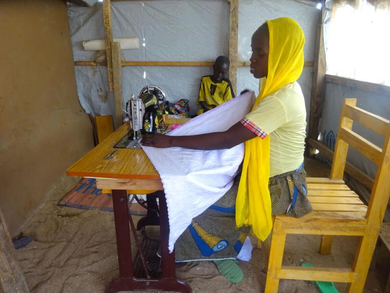 Esther working in a home reinforced with the ShelterBox tarpaulin