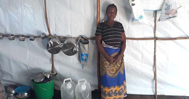 Modestar with water carriers, filters, and a kitchen set organized on a rack she built.