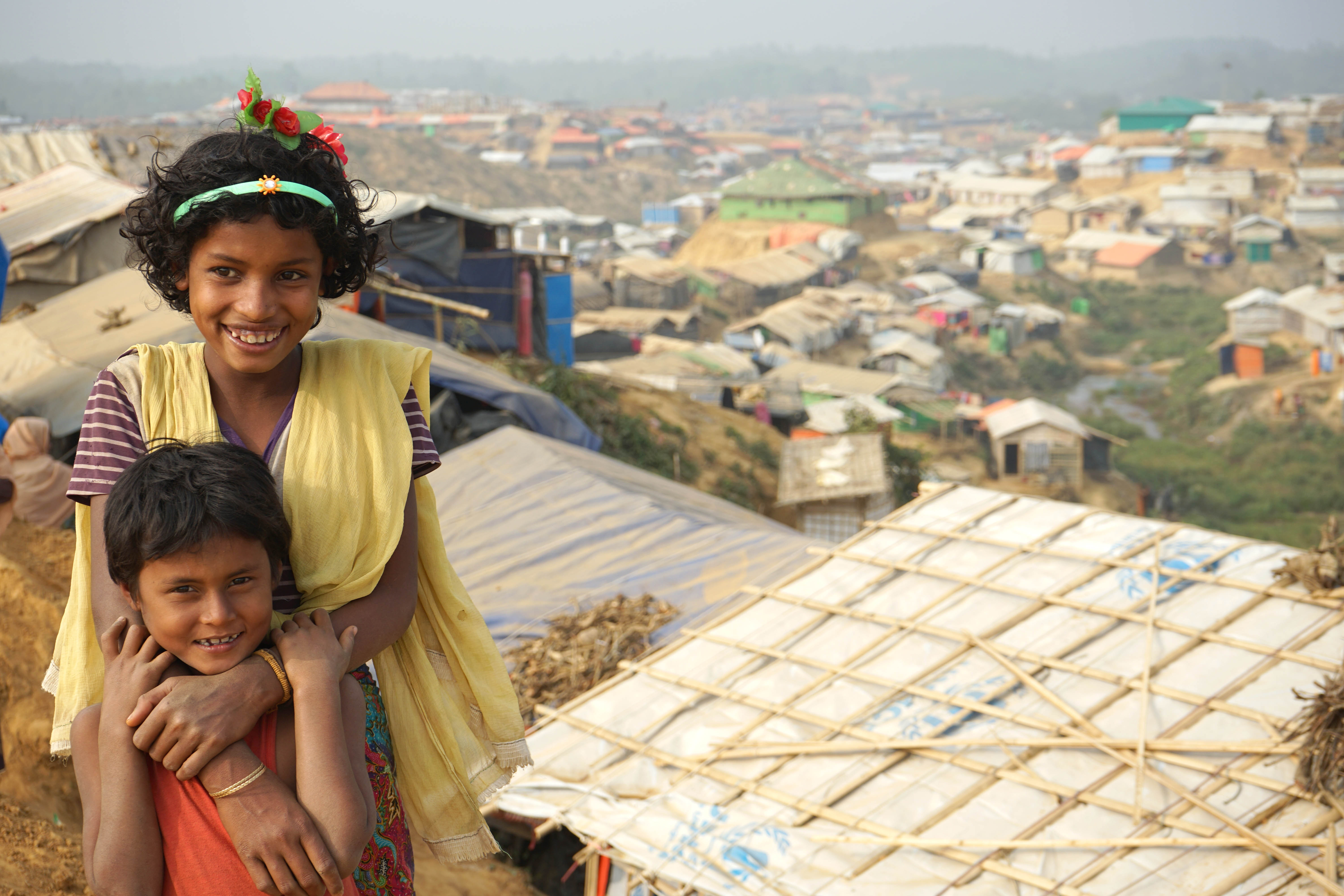 Children smiling in front of home with rebuilt roof