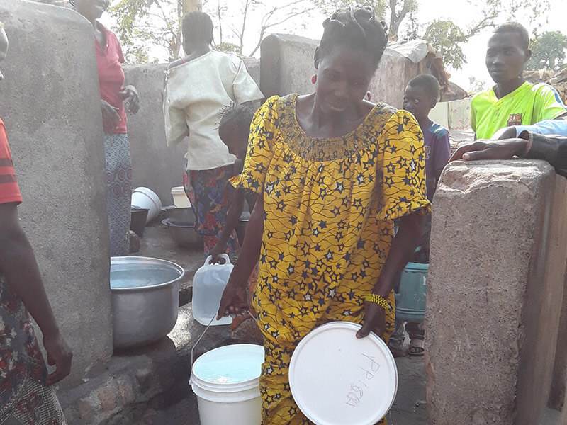 Rosalie and others gathering water, an essntial task that is delegated to female refugees 75% of the time