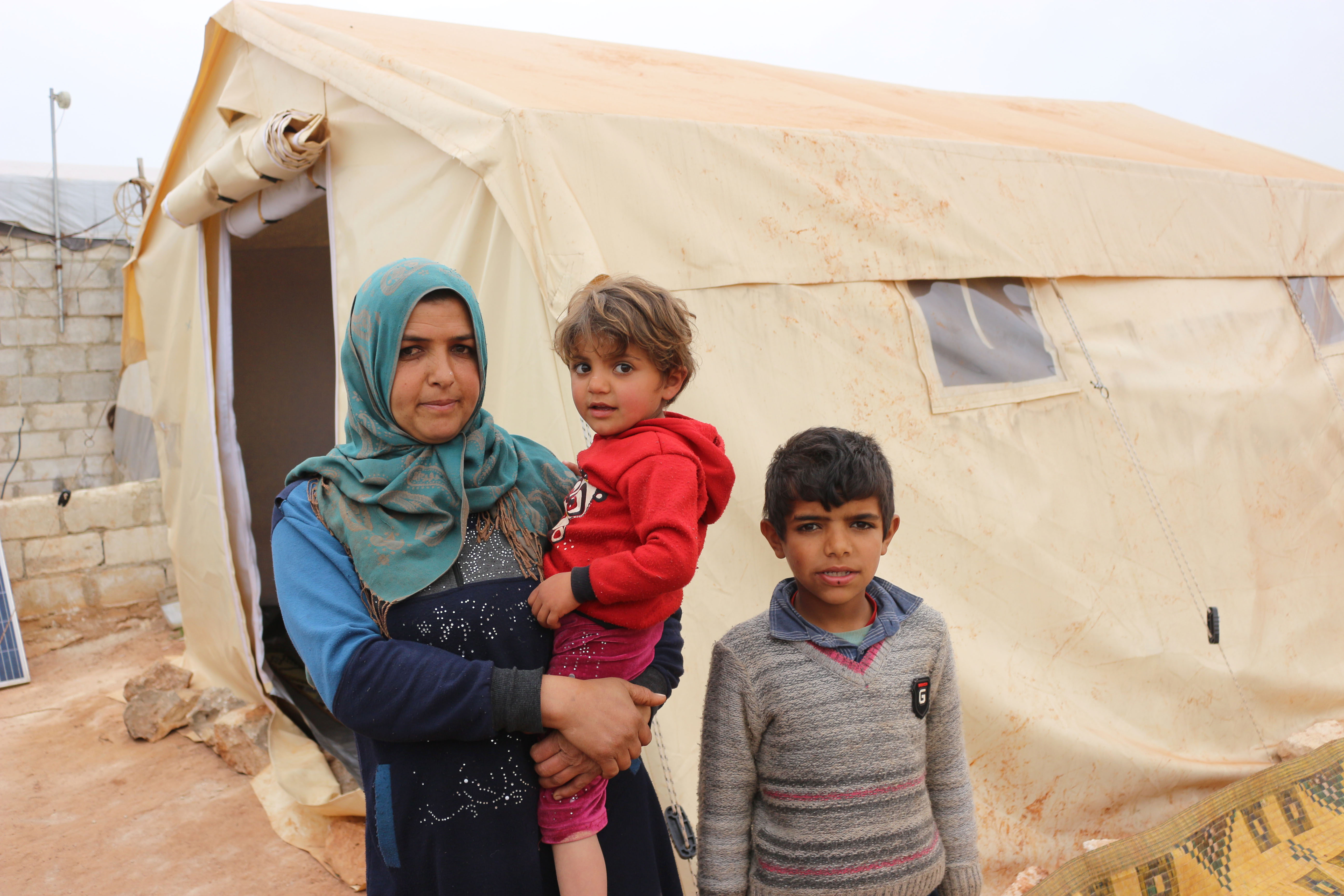 Woman and her two boys outside their tent