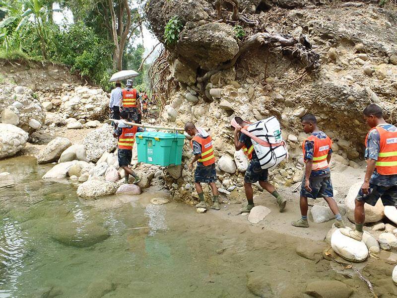 Carrying a heavy shelter box and kit over rocky terrain by a pond