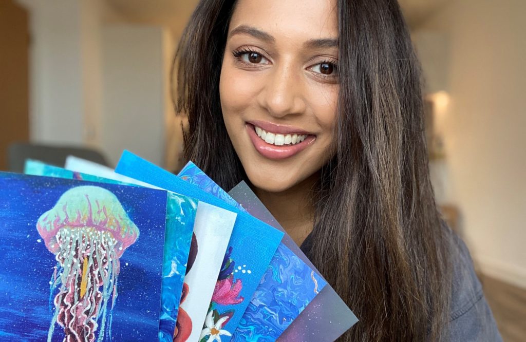 Rakhi showing 6 paintings; one is of a jellyfish