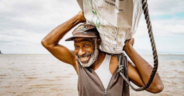 Man carrying shelter kit from a boat to land