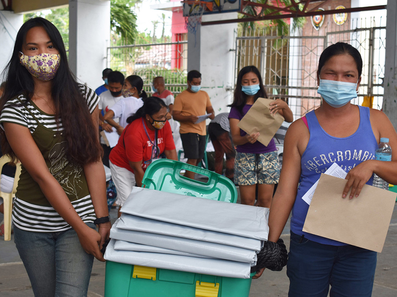 Filipino women with a ShelterBox and tarpaulin sheets