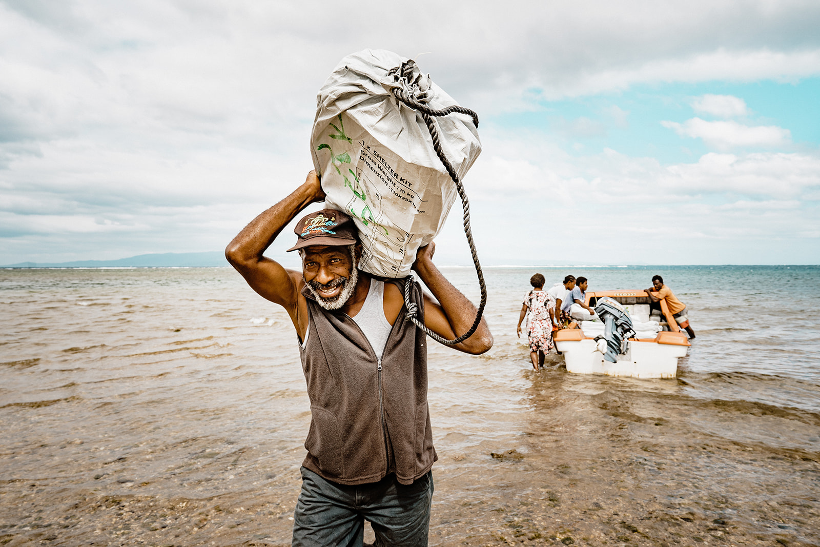 Man carries a shelter kit to land from a boat in Vanuatu