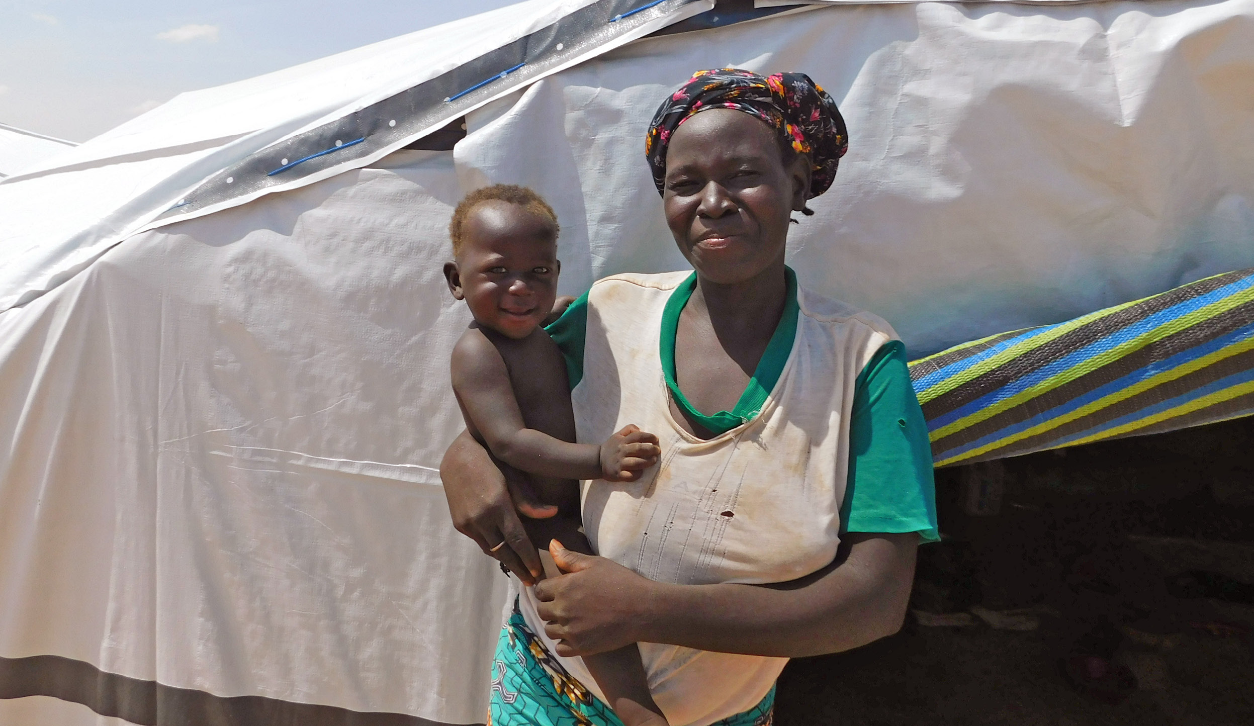 Woman outside tent holding smiling child