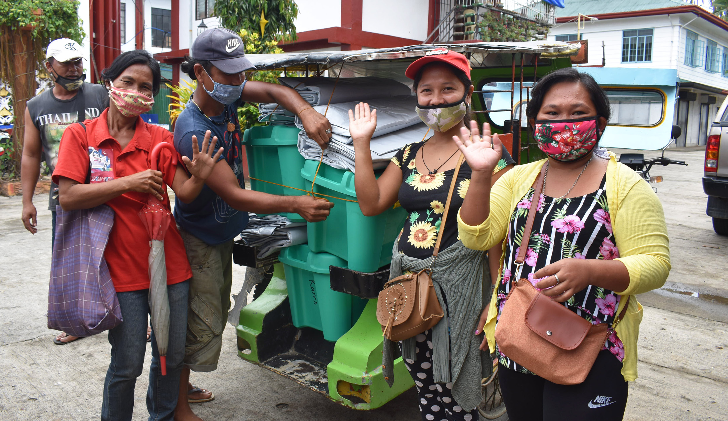 People moving aid items and wearing masks while waving to the camera