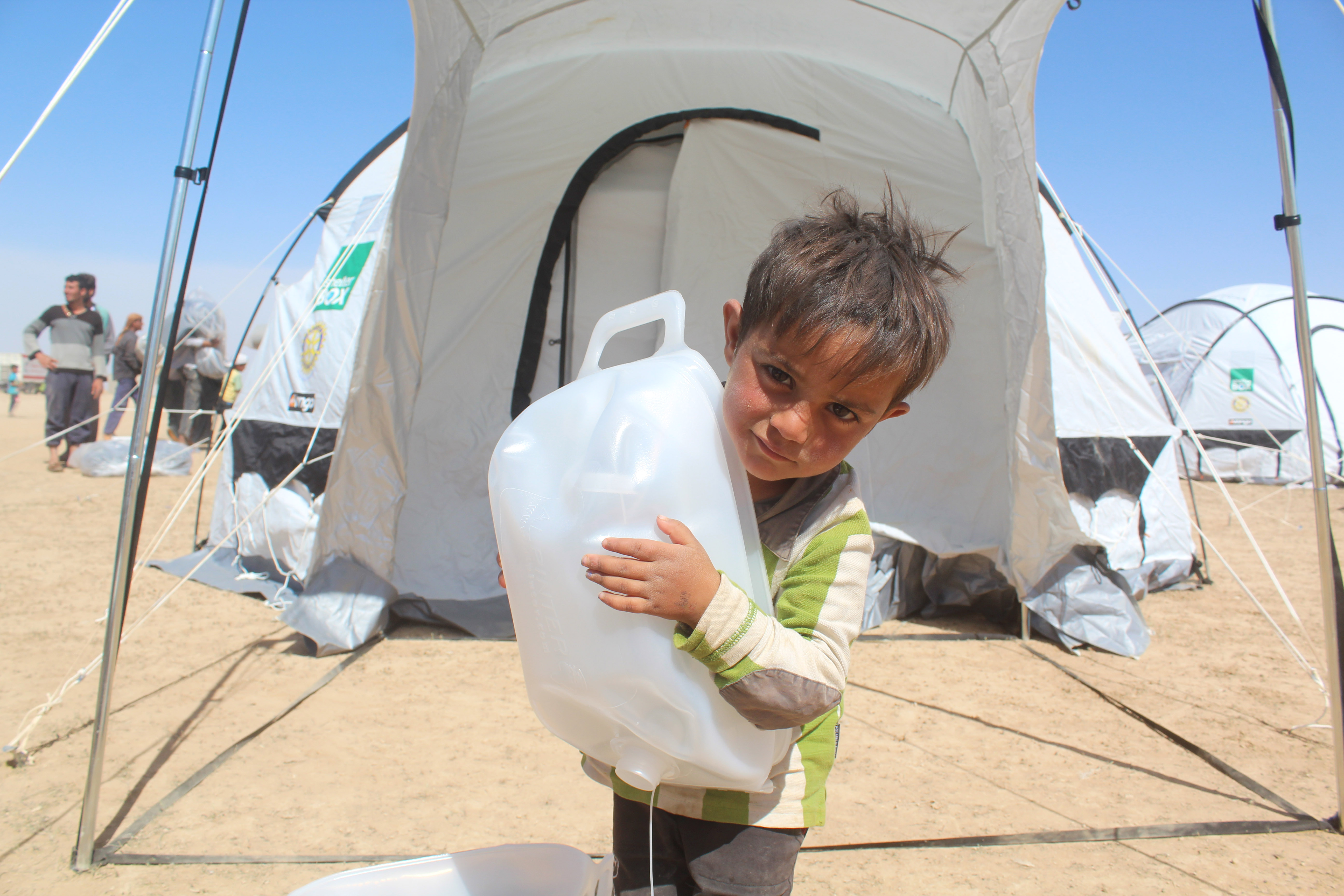 Young boy with a water jug that is bigger than he is