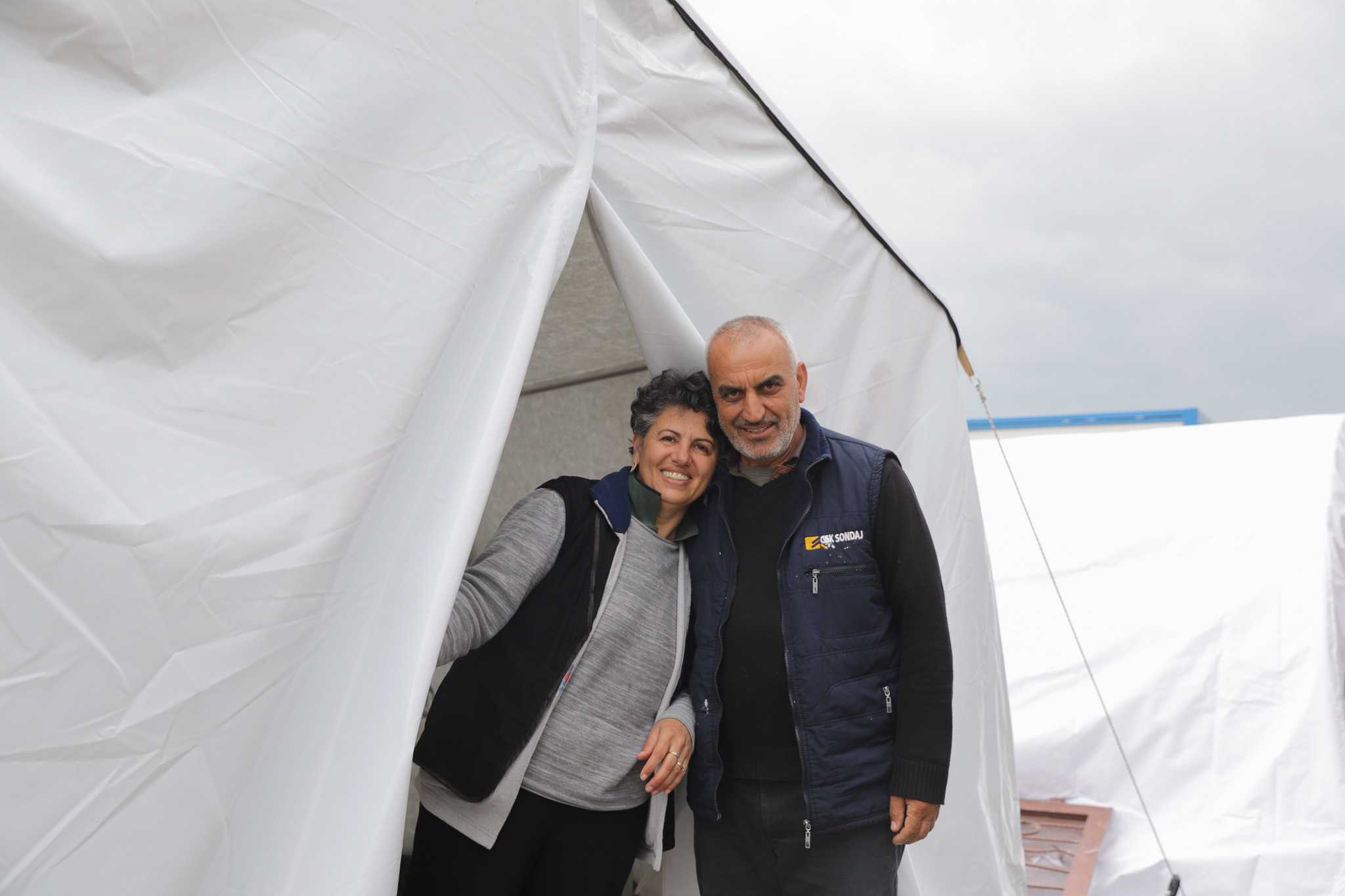 Nurgul and her husband stand in front of their ShelterBox Tent 