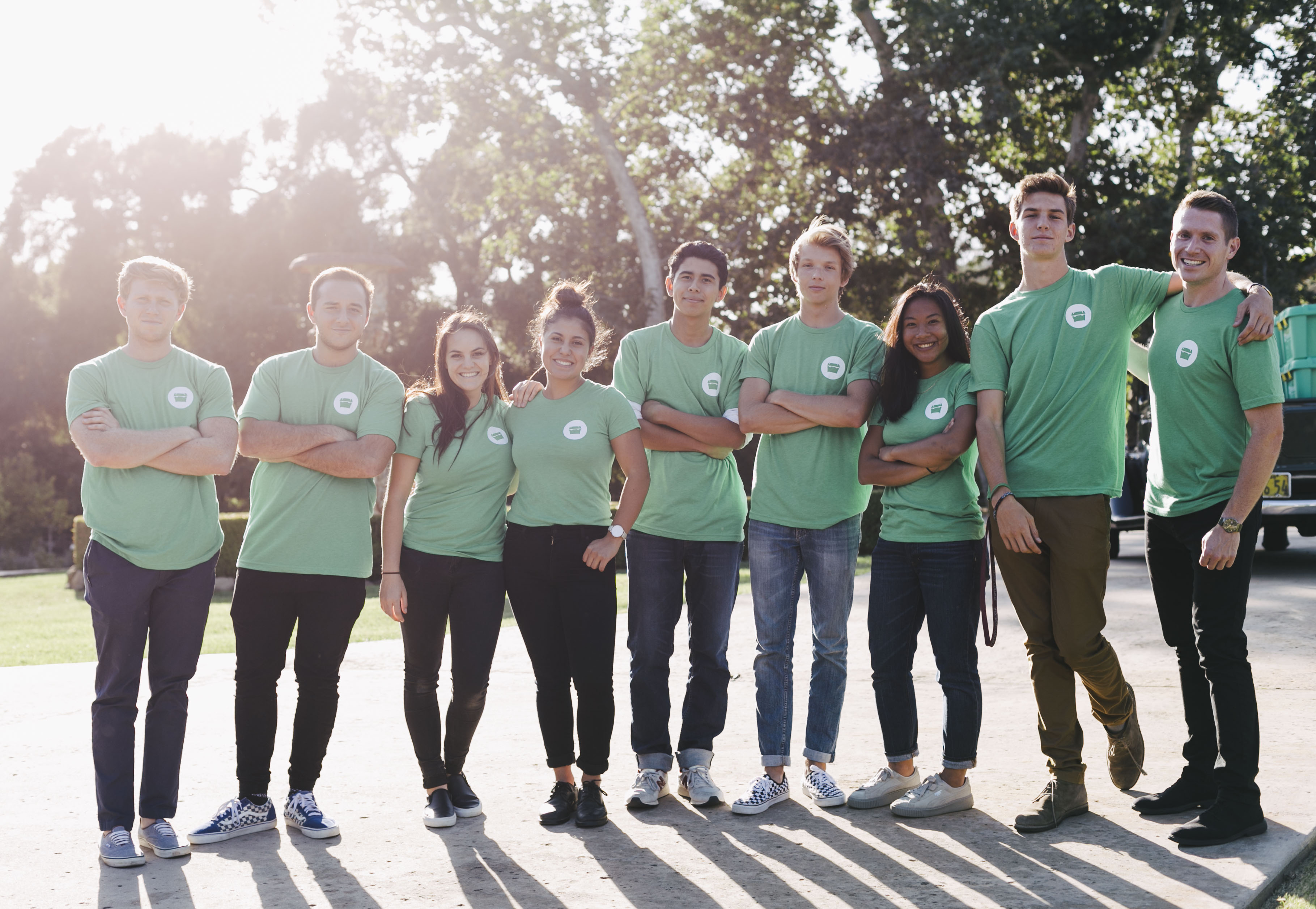 Nine people stand side by side, they're all wearing green ShelterBox t-shirts